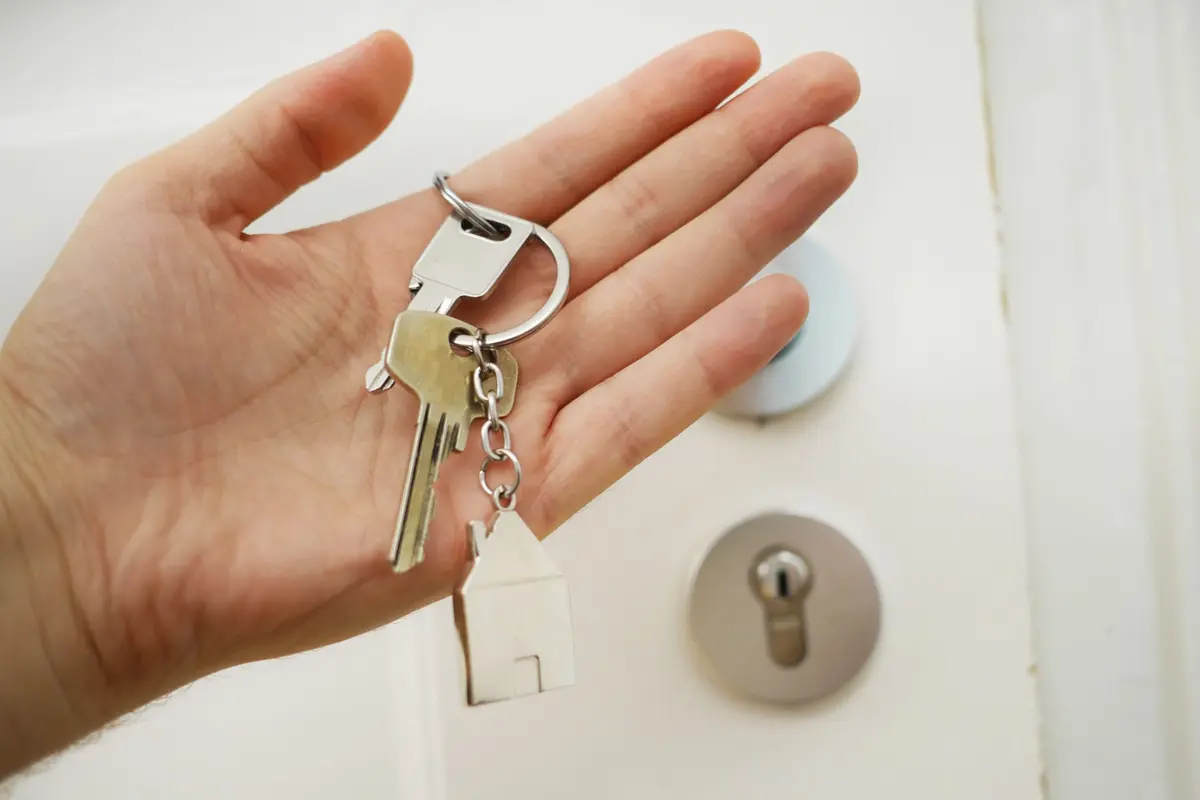 Remise d'un trousseau de clés devant la porte d'un logement